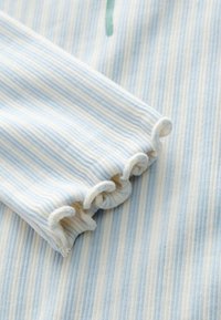 Lichtblauw en wit gestreept stof met een geribbelde textuur; heeft een gerimpelde manchetdetail. Materiaal ziet er zacht en lichtgewicht uit.