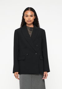 Blazer nero doppiopetto con design sartoriale, presenta rever a nota, due tasche frontali e dettagli con bottoni, realizzato in tessuto liscio.