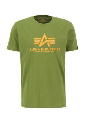 Olivovo zelené bavlnené tričko s okrúhlym výstrihom, na prednej strane s veľkým žltým grafickým logom a textom "ALPHA INDUSTRIES".