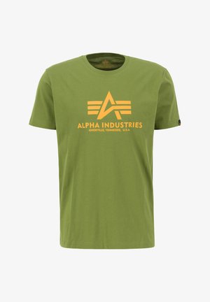 Olivovo zelené bavlnené tričko s okrúhlym výstrihom, na prednej strane s veľkým žltým grafickým logom a textom "ALPHA INDUSTRIES".