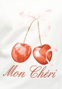 Δύο κόκκινα κεράσια με κοτσάνια δεμένα με ροζ κορδέλα πάνω από καλλιγραφικό κείμενο που γράφει "Mon Chéri" σε λευκό φόντο.