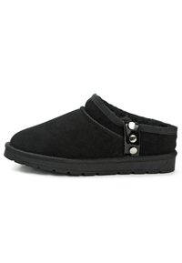 Schwarze Wildlederschuhe mit einem weichen Innenfutter, abgerundeter Spitze, gesticktem Detail und zwei dekorativen schwarzen Knöpfen an der Seite.