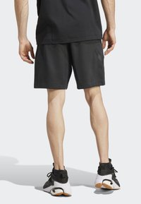 Melnas sporta šortus ar sānu kabatām, standarta piegriezums, izgatavoti no mīkstas auduma, apvienoti ar melnbaltiem kedām ar teksturētu zoli.