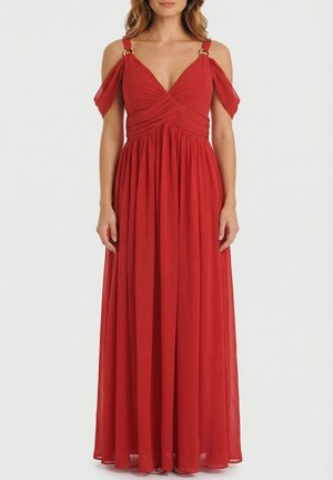 Mujer con vestido maxi rojo sin mangas, con tela drapeada fuera del hombro y detalles de tirantes con anillos dorados.