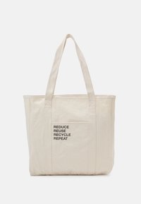 Canvas shoppingväska i ljusbeige med texten "MINSKA ÅTERANVÄND ÅTERVINNA UPPREPA" i svart. Har två robusta handtag och en sidoficka.