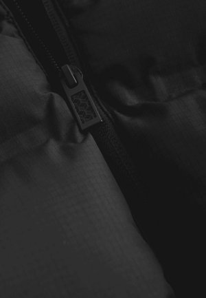 Black puffer jacket section featuring a textured fabric, zip closure with a hexagonal patterned pull tab, and smooth, padded appearance.