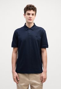 Pólo azul marinho feito de algodão, com colarinho clássico, dois botões, mangas curtas e um pequeno logótipo bordado no peito.