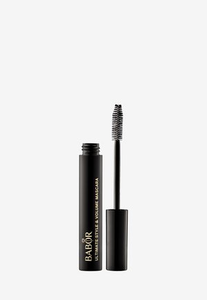 Schwarze Mascara-Tube mit goldener Schrift, Kappe entfernt, begleitet von einem gebogenen Bürstchen mit kurzen Borsten für die Anwendung.