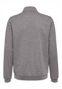 Set bagfra af en ensfarvet grå langærmet pullover med ribbet kant ved ærmer, bund og en opretstående krave.