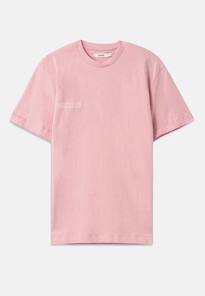 T-shirt de manga curta rosa claro feito de algodão. Apresenta um decote redondo e um pequeno detalhe de texto impresso na área do lado esquerdo do peito.
