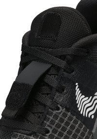 Scarpa sportiva nera con tomaia testurizzata, chiusura con lacci, dettagli del logo, toppa e un design di supporto con una finitura elegante e moderna.