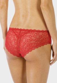 Rode kanten ondergoed met een golvende tailleband en bloemmotief. Translucente netpanelen zorgen voor contrast en textuur aan de achterkant.