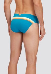 Slip da bagno blu con una vestibilità aderente, caratterizzato da un motivo a righe orizzontali colorato in arancione, bianco e giallo lungo la vita.