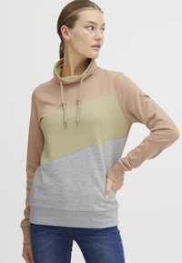 Felpa con cappuccio in beige, oliva e grigio. Presenta una vestibilità morbida, blocchi di colore a contrasto e lacci al collo. Texture morbida.