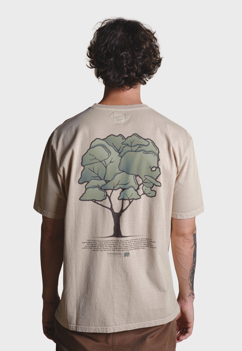 Beige bavlněné tričko s velkým zeleným grafikou stromu na zadní straně, s detailními konturami a textem pod ním, krátké rukávy, volný střih.