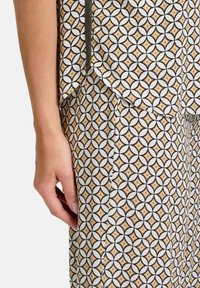 Textiloutfit med ett geometriskt m�önster med sammanlänkade cirklar och diamanter i svart, vitt och guldfärger. Mjuk tyg, avslappnad passform.