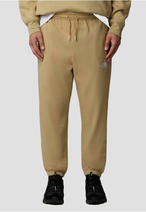 Beige sweatpants made from fabric with a soft texture, featuring an elastic waistband and cuffs. A small logo is visible on the left thigh.