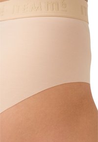 Mutande alte beige in tessuto liscio con una morbida fascia in logo goffrato, caratterizzate da un design senza cuciture per garantire comfort.