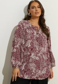 Blusa floreale bordeaux con maniche lunghe a sbuffo, con scollatura con lacci e motivi botanici bianchi su tessuto leggero.