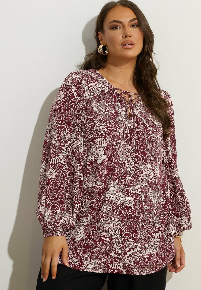 Blusa floreale bordeaux con maniche lunghe a sbuffo, con scollatura con lacci e motivi botanici bianchi su tessuto leggero.