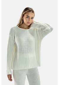 Vit ribbad stickad tröja med lång ärm och rund halsringning, matchad med ribbade leggings i samma material. Lättviktig, strukturerad tyg.