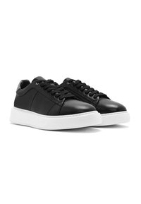 Sneaker in pelle nera con pannello laterale testurizzato, suola piatta in gomma bianca, lacci neri e design a punta arrotondata.
