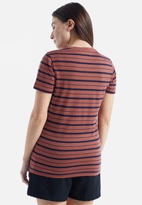 Striped T-shirt in rusty orange with navy blue horizontal stripes, short sleeves, round neck, and a fitted design, worn with black shorts.