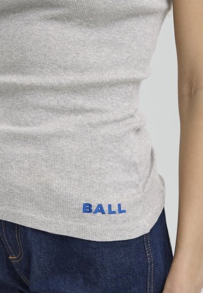 Světle šedý žebrovaný tílko s modře vyšitým nápisem "BALL" na dolním lemu, spárované s tmavě modrými džíny.