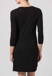 Robe noire à manches trois-quarts avec un col rond, silhouette ajustée, texture lisse, et longueur au genou.