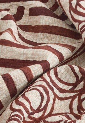Tissu avec un fond beige présentant des motifs abstraits circulaires et rayés en rouge foncé. Texture douce avec une apparence tissée.
