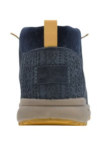 Zapato alto de ante azul marino con patrón de tejido texturizado, lengüeta amarilla y suela de goma color canela. Cuenta con un tacón ligeramente elevado.