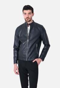 Giubbotto in pelle nera con colletto alto, chiusura frontale con zip e due tasche laterali con zip, caratterizzato da una texture liscia e un design aderente.