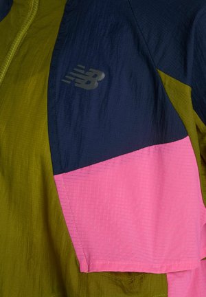 Sezione della giacca a blocchi di colore in verde oliva, blu navy e rosa con un logo riflettente New Balance sul tessuto blu navy.