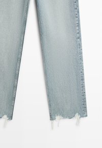 Hellblaue Jeans aus Denim mit ausgefransten Säumen, die ausgefranste Kanten und ein gerades Bein aufweisen. Sichtbare Nähte entlang der Seiten.