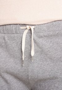 Gray sweatpants with an elastic waistband; features a beige drawstring with metal tips, and a smooth, soft texture.