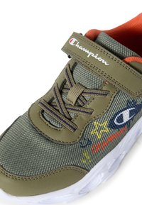 Zielone siatkowe buty sportowe z pomarańczowym wnętrzem, z czarnymi sznurówkami, rzepem oraz wielokolorowymi akcentami logo po bokach.