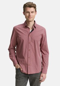 Rot-weiß karierter Hemd mit langen Ärmeln, Kragen und braunen Knöpfen, kombiniert mit dunkelgrauen Jeans.