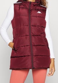 Bordowy kamizelka puchowa z kapturem i zamkiem błyskawicznym, z poziomymi przeszyciami, małym logo na piersi oraz bocznymi kieszeniami.