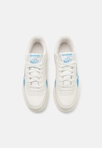 Balti odiniai sportbačiai su šviesiai mėlynomis akcentais, perforuotais detalėmis ir baltais raišteliais. Reebok Classic logotipas ant liežuvėlio. Minkšta vidinė pamušalas.