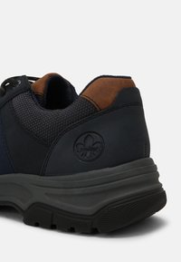 Navy sneaker with a padded collar, leather accents, mesh panels, and a textured black rubber sole. Features a branded logo on the heel.