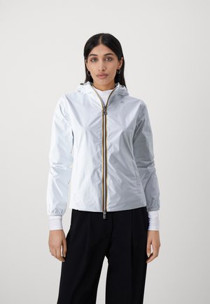 Giacca a vento leggera, di un blu pallido, con zip frontale, cappuccio regolabile, polsini elasticizzati e dettaglio della zip gialla a contrasto.