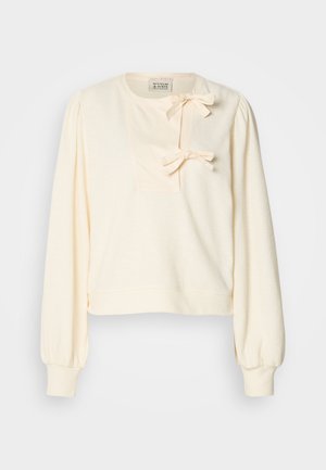 Cremefarvet sweatshirt med lange puffærmer, der har en tekstureret forpatch og to dekorative sløjfer ved halsudskæringen.