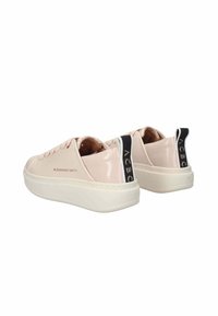 Pinke Lacklederschuhe mit weißer Sohle, ausgestattet mit einem schwarzen Fersenpatch mit Logo und minimalen Schnürdetails. Glatte Textur und schlankes Design.