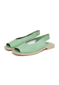 Paire de sandales slingback en cuir vert clair avec orteils ouverts et semelles plates beiges sur fond blanc.