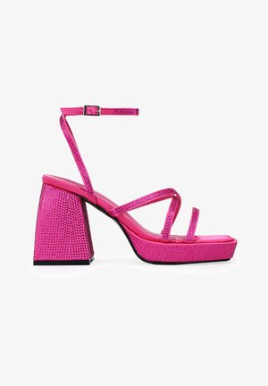 Pink platform sandals featuring a block heel and ankle strap, adorned with rhinestones on the upper and heel for added texture and detail.