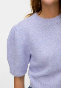 Lila pletena pulover s kratkimi, napihnjenimi rokavi; puhasta tekstura in rebrast ovratnik. Mehka, lahka tkanina, ki ima sproščen kroj.