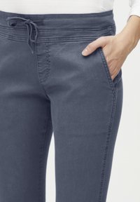 Pantalones de mezcla de algodón grises con cintura ajustable, bolsillos laterales y una textura suave, con costuras cosidas y un ajuste estrecho.