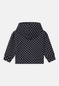 Mörkblå hoodie med vita prickar, med huva, långa ärmar och ribbad mudd. Designad med en kortad passform och mjuk textur.