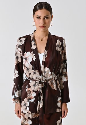 Veste kimono florale en marron foncé, présentant un design enroulé, des manches longues et une ceinture. Fabriquée en tissu doux avec de grandes fleurs crème et roses.