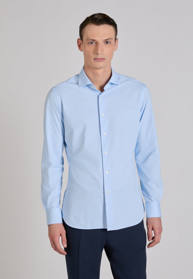 Camisa azul claro de tela lisa con mangas largas y cuello clásico, con un corte ajustado y botones blancos.